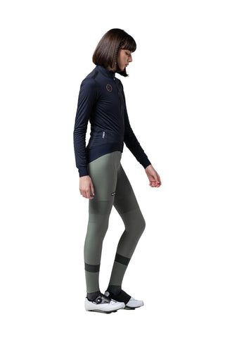 Ciclista donna con giacca Gobik Armour 2.0 Ultrablue blu navy e calzamaglia verde oliva, abbigliamento tecnico invernale per bici da strada.