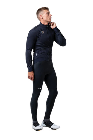 Ciclista uomo con giacca Gobik Armour 2.0 Ultrablue blu navy e calzamaglia nera, outfit tecnico per ciclismo invernale su strada.