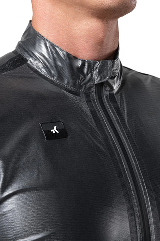 Ciclista donna con giacca Gobik Pluvia 2.0 unisex nera, antivento e traspirante per allenamenti sotto la pioggia.