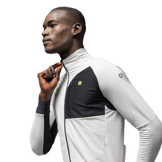 Ciclista uomo indossa giacca ciclismo invernale Alè R-EV1 Riparo colore stucco e nero, vista tre quarti con zip frontale – abbigliamento tecnico idrorepellente per bici da corsa