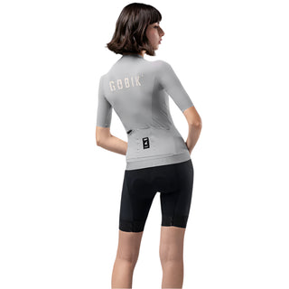 Maglia ciclismo donna Gobik grigio indossata retro – design con tasche posteriori e logo riflettente, comfort e funzionalità per ciclismo su strada