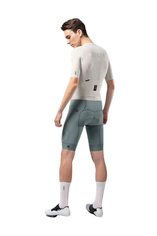 Uomo di spalle che indossa maglia da ciclismo Gobik CX Solid Argonite bianca, pantaloncini grigi, calze bianche.