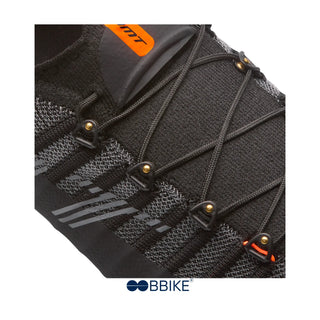 Dettaglio occhielli rinforzati e sistema di chiusura a lacci incrociati delle scarpe da ciclismo DMT Pogis nere, con tessuto Knit tecnico e inserti riflettenti, progettate per calzata anatomica e performance su strada.