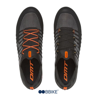 Vista dall’alto delle scarpe da bici su strada DMT Pogi’s nere con lacci arancioni e neri, struttura anatomica in mesh tecnico traspirante e suola full carbon.
